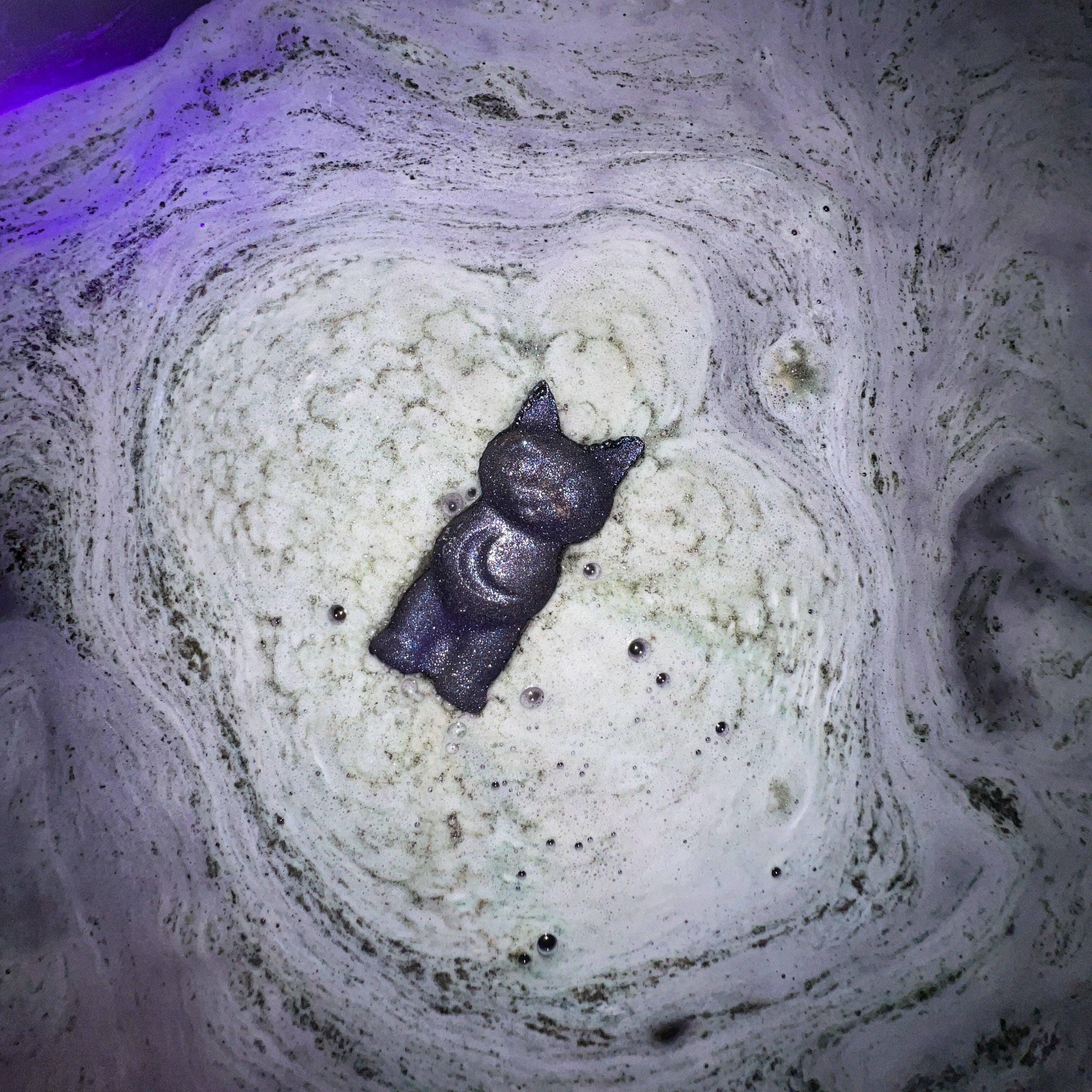 Small black cat bath bomb dissolving in a bath